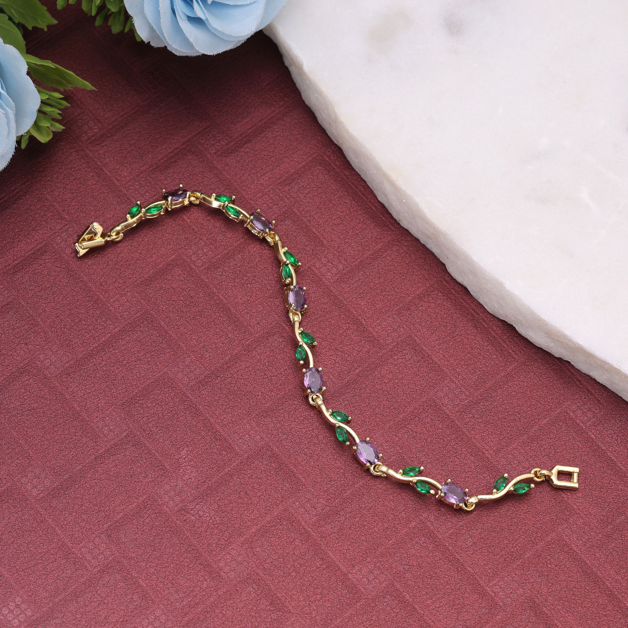 A delicate gold-plated chain bracelet featuring an organic vine and leaf branch design embedded with multi-color oval and marquise-cut cubic zirconia stones secured with a polished watch-band foldover clasp.