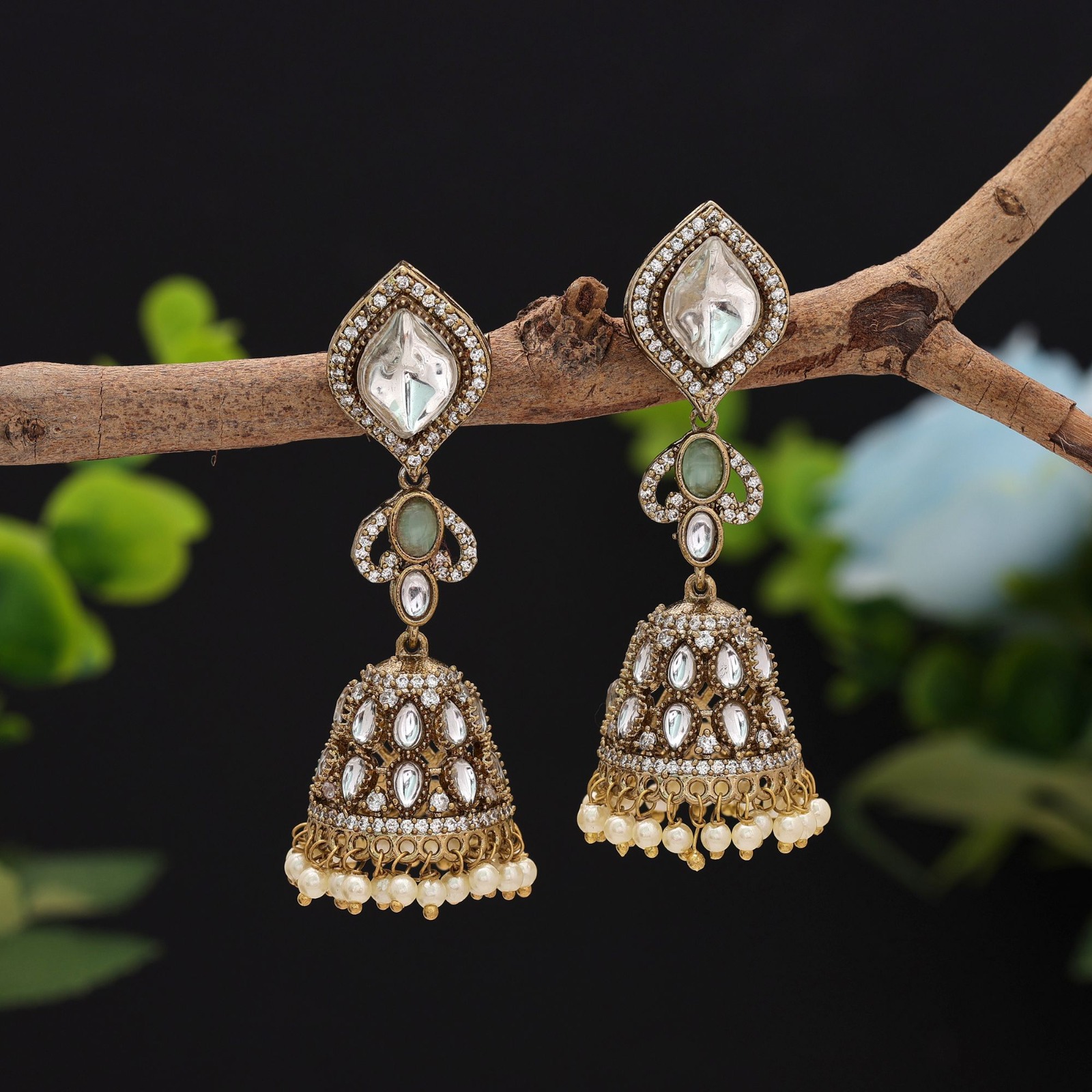 Pair of antique gold statement jhumka earrings featuring diamond-shaped Kundan studs, oval mint green Monalisa stones, and pearl-edged dome drops.