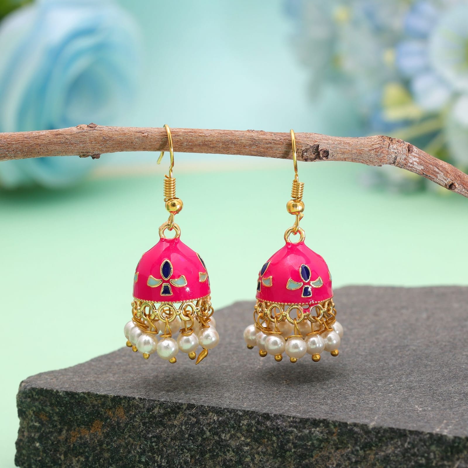 Pair of lightweight gold-toned white enamel Meenakari jhumka earrings with red and green floral accents and pearl drops, suitable for daily and occasion wear.