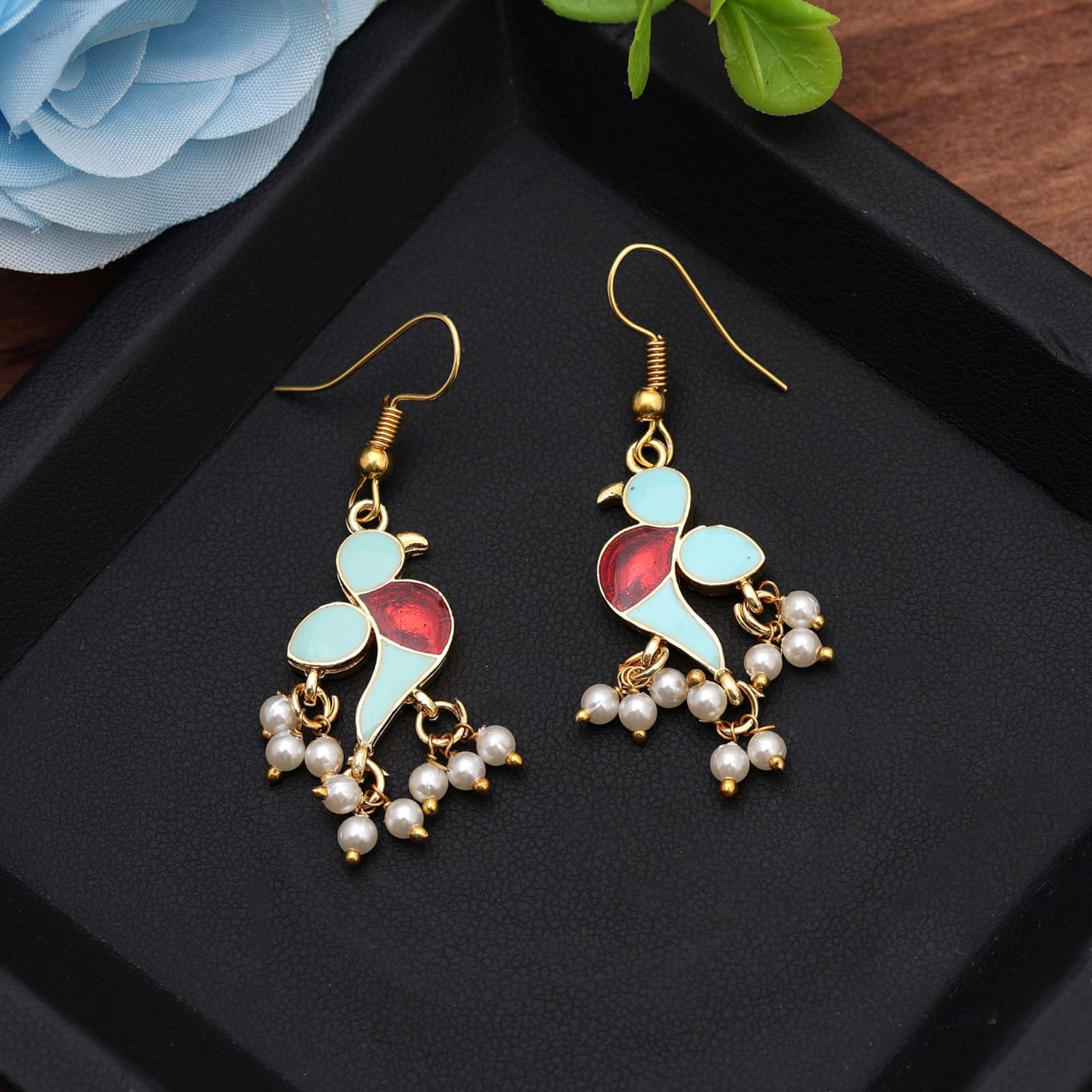 Elevate your ethnic collection with these gold-plated meenakari bird dangle earrings. Crafted in a charming bird motif accented with light blue enamel, deep red detailing, and delicate white pearl cluster drops, this handcrafted pair brings traditional Indian flair and modern charm to festive outfits, weddings, and casual traditional wear.