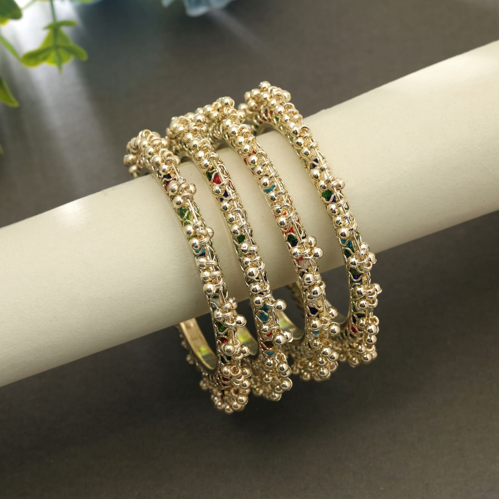 Gold-plated Indian traditional bangles set decorated with multicolor beads and small metallic ghungroo cluster borders.